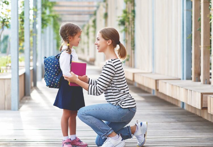 first day at school. mother leads a little child school girl in first grade